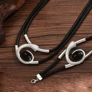Close-up detail of bohemian style spiral snail shape black gemstone necklace bracelet jewelry set.