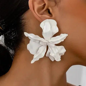Gros plan détaillé d'une boucle d'oreille florale blanche oversize portée par un mannequin.