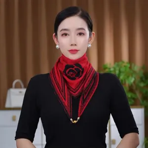 Detail shot of the red knitted triangle scarf featuring a black camellia pattern and magnetic clasp.