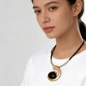 Gold-toned metal spiral statement necklace with black acrylic stone for women fashion wear.