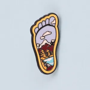 Footprint mountain landscape enamel pin detail shot, metal lapel badge accessory.