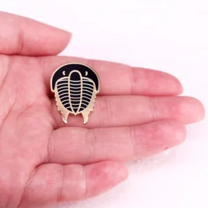 Detailed close-up of a trilobite metal brooch, exquisite black and gold enamel pin decor.