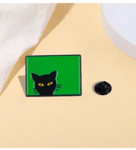 Vista dettagliata della spilla smaltata con gatto nero e sfondo verde, accessorio zaino.