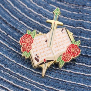 Leuke emaillen speld met een boek doorboord door zwaard en rode rozen, stijlvolle badge.