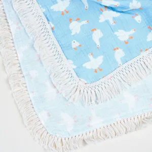 Nahaufnahme der weichen Baumwoll-Musselin-Babydecke mit süßem Entenmuster und Fransen.