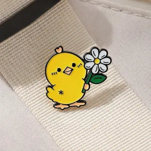 Close-up detail of cute yellow chick holding daisy enamel pin, creative alloy badge.