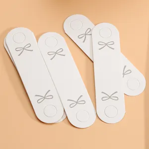 Weiße Papierverpackungskarten mit grauen Schleifendesigns für DIY-Armbänder und Haargummis.