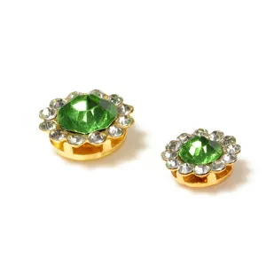 Close-up of DIY round floral rhinestone buttons with green center stones and gold bases.