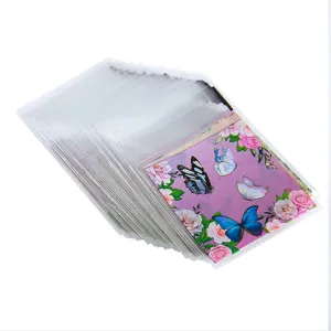 Detalle de la bolsa de celofán transparente con tarjeta de mariposa y rosa decorativa.