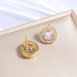 Gedetailleerde close-up van gouden oorknopjes met fonkelende strass-steentjes en halo.