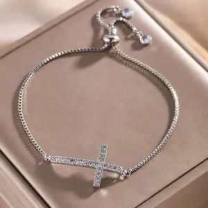 Elegant zilverkleurig armbandje met zirkonia kruis detail en glinsterende steentjes.