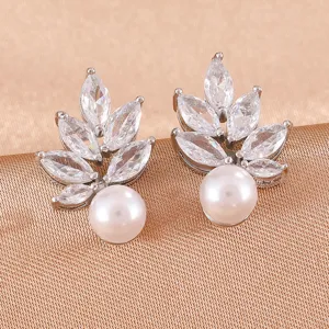 Gedetailleerde close-up van elegante oorbellen met zirkonia en parel in bladvorm.