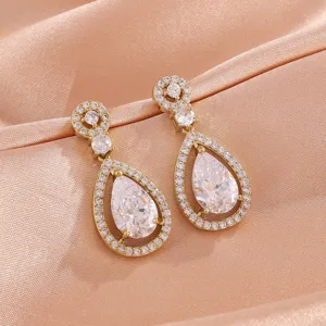 Gedetailleerde close-up van luxe peervormige zirkonia hangende oorknoppen in gouden afwerking.