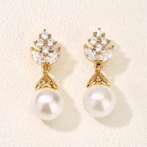 Gedetailleerde close-up van elegante vergulde oorbellen met sprankelende zirkonia en parel.