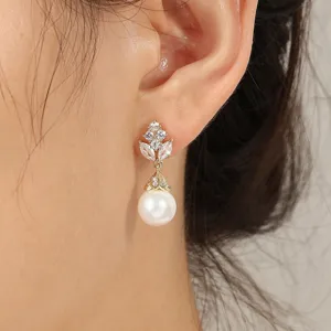 Gedetailleerde close-up van elegante goudkleurige oorbellen met blad zirkonia en parel.