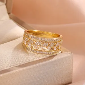 Elegante brede vergulde ring met opendewerkt bladontwerp en sprankelende zirkonia's.
