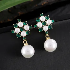 Detailopname van elegante parel en groene zirkoon bloem hangende oorbellen in goudkleur.