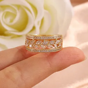 Detail van brede gouden ring met zirkonia stenen en opvallend opengewerkt bladeren motief.
