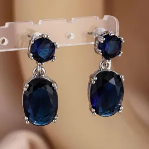 Close-up van elegante blauwe zirkonia oorbellen met dubbele hanger in mooie zilveren zetting.
