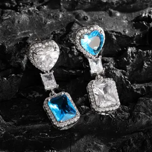 Close-up van luxe hart en rechthoekige zirkonia oorbellen met fonkelende stenen en details.