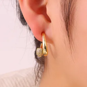 Detailopname van stijlvolle gouden C-vormige oorbellen met sprankelende zirkonia stenen.