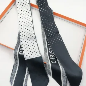 Close-up view of black and white polka dot silk twilly hair scarf for bags and hair.