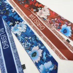 Detail view of floral print twilly silk scarf ribbon with letter stripe pattern for bags.