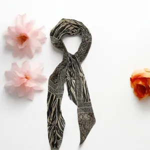 Detail view of a chic patterned skinny scarf featuring a sophisticated animal print and polka dot mix.