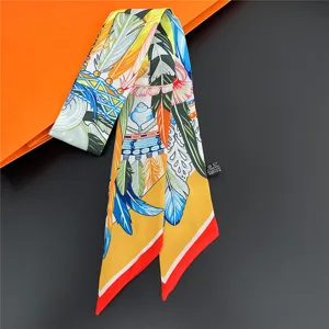 Detailed view of colorful printed twilly silk scarf with feather pattern, elegant accessory.