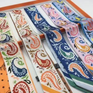 Detailed view of elegant silk twilly scarves in orange gift box, perfect for handbag handle and hair.