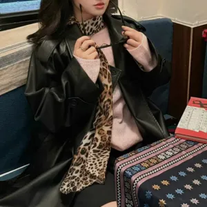 Detailed shot of a chic leopard print silk scarf styled with a black leather coat and sweater.