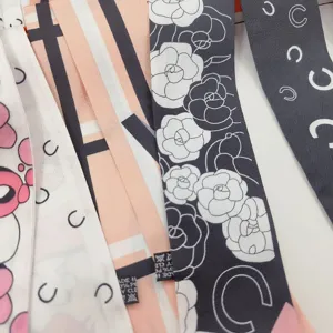 Gros plan détaillé du foulard en soie étroit Twilly élégant avec motif classique de camélia.