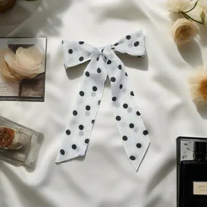 Detail view of white silk ribbon with black polka dots, featuring soft lightweight fabric.