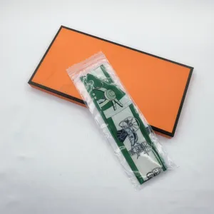 Green silk twilly scarf with carriage print and orange gift box for handbag decoration.