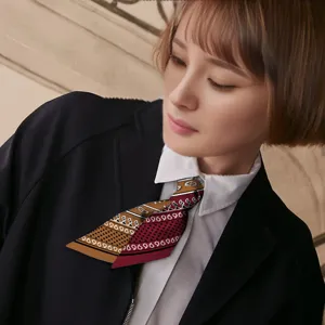 Close-up detail of the elegant paisley ribbon scarf showing its unique color-blocking design.