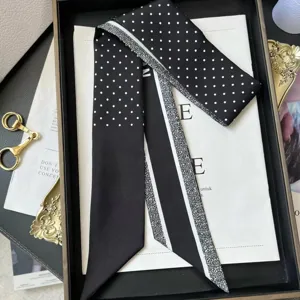 Detailed view of black and white polka dot skinny silk scarf, elegant accessory for handbag handle.