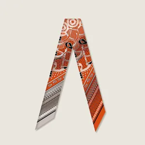 Detailed view of the orange twilly silk scarf with luxury bridle print and chic chain motifs.