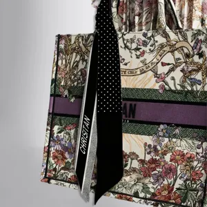 Detail view of printed twilly scarf tied on embroidered floral tote bag handle fashion.