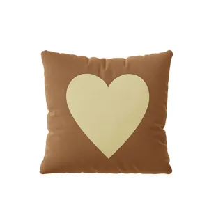Gros plan sur les détails du coussin carré marron avec motif cœur crème et douce texture.