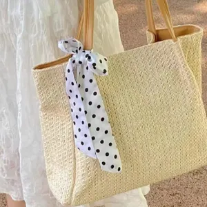 Close-up detail of a stylish black and white polka dot scarf tied on a straw tote bag.