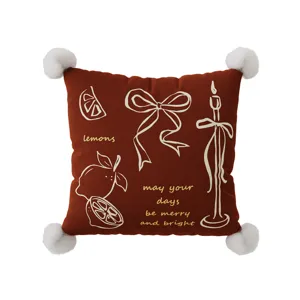 Close-up detail of red velvet cushion cover featuring cute white pom-poms and lovely lemon line art.
