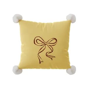 Yellow square throw pillow detail featuring white pom-poms and brown bow print.