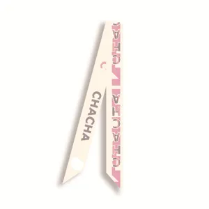 Gros plan detail d'un foulard en ruban de soie etroit avec motif chic et ton blanc casse.