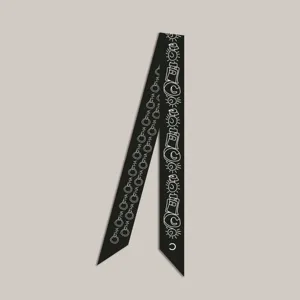 Élégant foulard en soie noir étroit avec motifs imprimés blancs, idéal pour sacs ou cou.