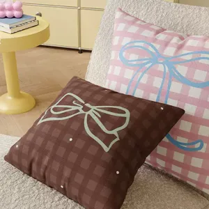 Detailed view of cozy checkered throw pillows with cute bow designs in a warm indoor home setting.