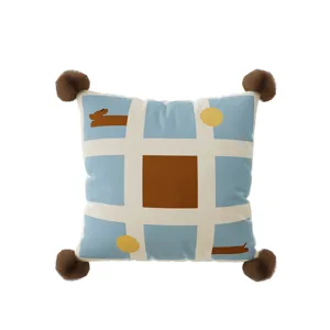 Detail shot of the square throw pillow cover featuring blue grid, abstract patterns, and pom poms.