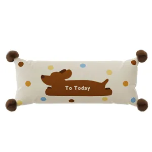 Cute long bolster pillow detail featuring a brown dog print and fluffy pom-pom corners.