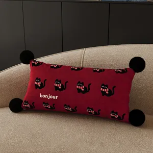 Red cat pillow detail showing cute black cats with scarves and corner pom pom decor on sofa.