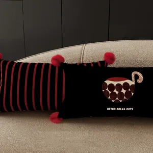 Close-up detail of retro striped and polka dot throw pillows with red pom-pom decor on a sofa.
