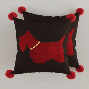 Set di due cuscini quadrati decorativi con pon pon rossi e cane terrier nero.